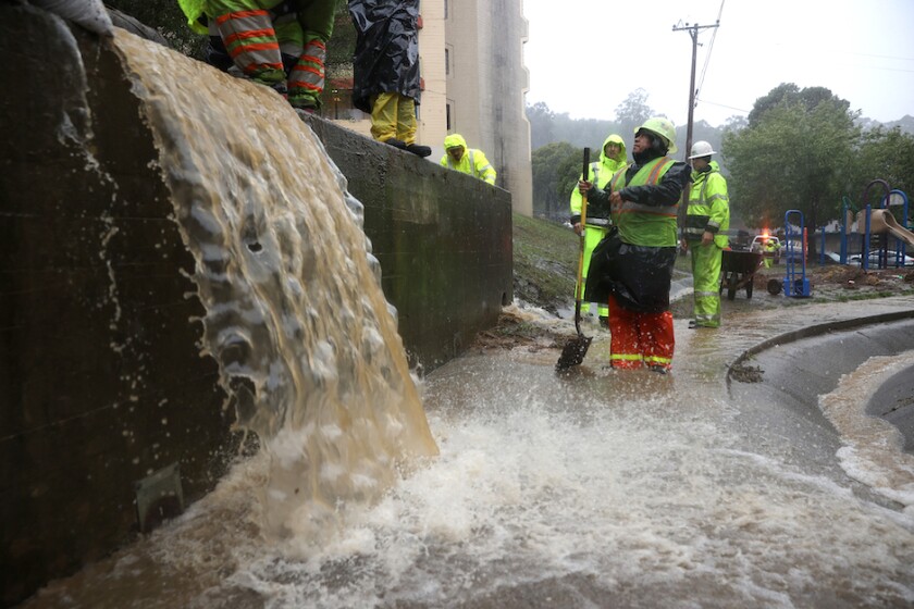 Workers in Marin County attempting to manage rainwater overflow from a storm.