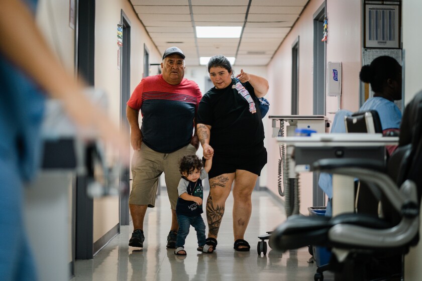 Policarpo Landaverde walks with his daughter, Crystal Landaverde, and her son, King, in a hallway at the Doris Ison Health Center