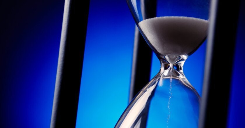A close-up of an hourglass with a blue background