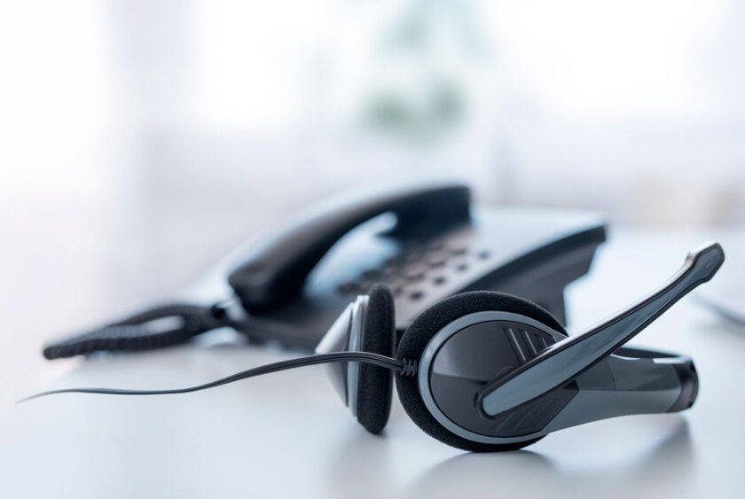 A+headset+sits+next+to+an+office+phone+on+a+desk