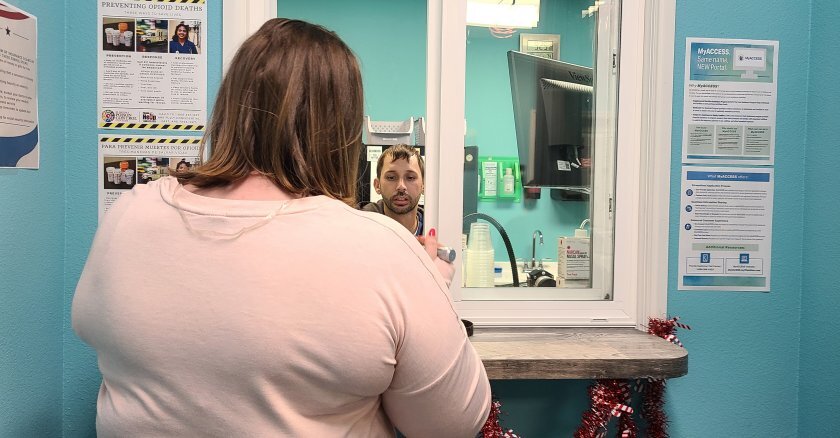 A client picking up her methadone prescription at a pharmacy window.