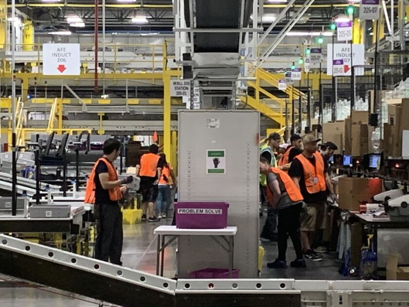 Many workers in orange vests inside the Amazon warehouse in Clay, N.Y.