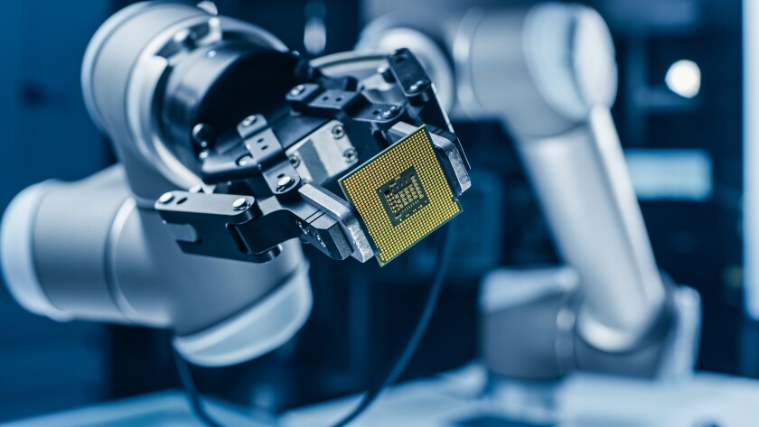 A silver robotic arm holding a yellow microchip.