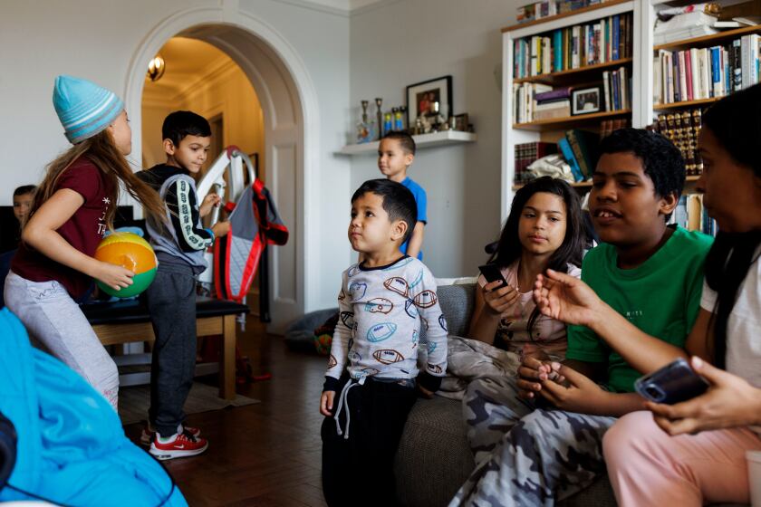 Josue, 4, center, stands with other migrant families in Mary Otts-Rubenstein's home