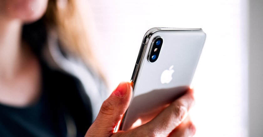 A person holding up an iPhone X.