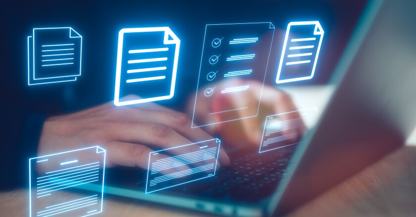 Closeup of hands typing on a laptop with blue icons of documents hovering in front of them.