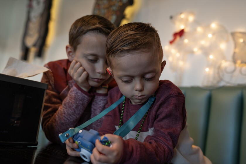 two young boys play a game on a toy camera