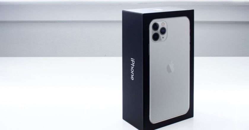 An unopened iPhone box standing on it's end on a white surface.