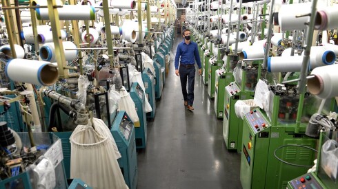 A man wearing a face mask walks through a factory.