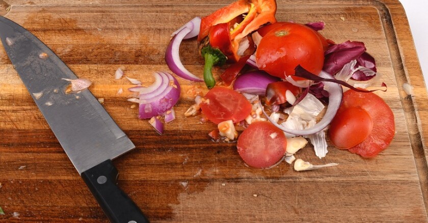 Food scraps and a knife on a cutting board.