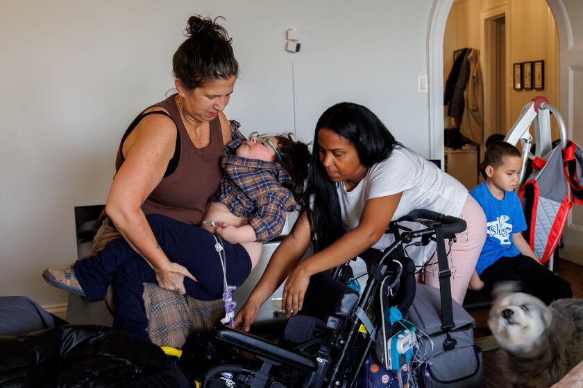 a woman helps put a child into a wheelchair