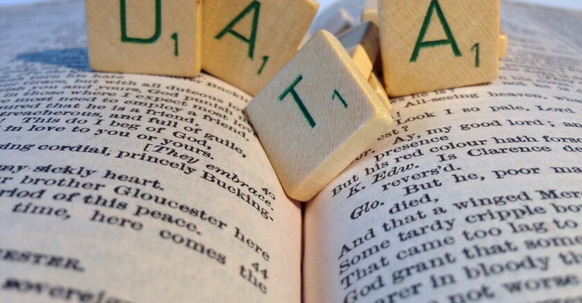 Closeup of wooden tiles that spell "data" resting on an open book.