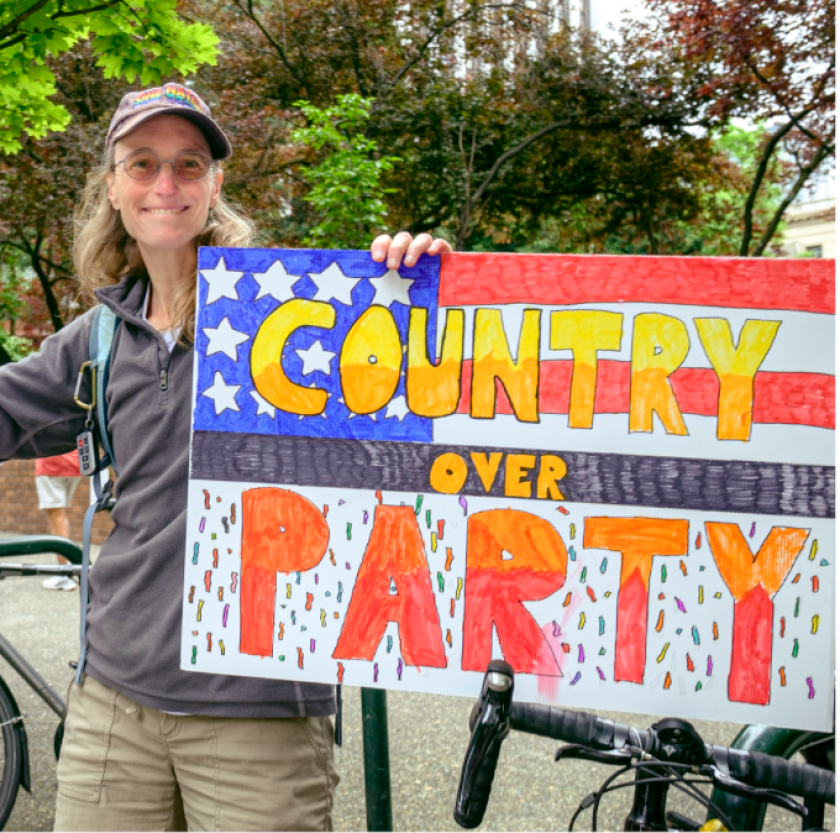 A demonstrator holding a sign that reads “country over party.”
