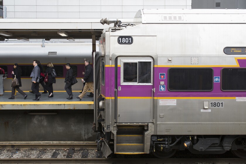 The front car of a train stopped at the station with people walking past it on the platform.