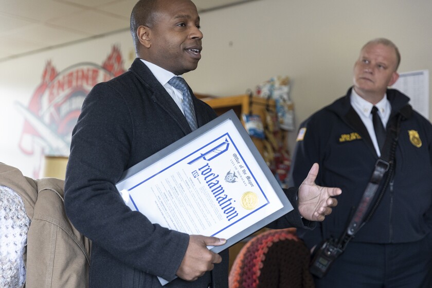 Milwaukee Mayor Cavalier Johnson holding a proclamation document while speaking.