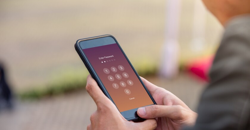 Man typing passcode on smartphone.