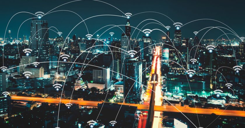Wi-Fi symbols connected by lines hovering above a city skyline at night.