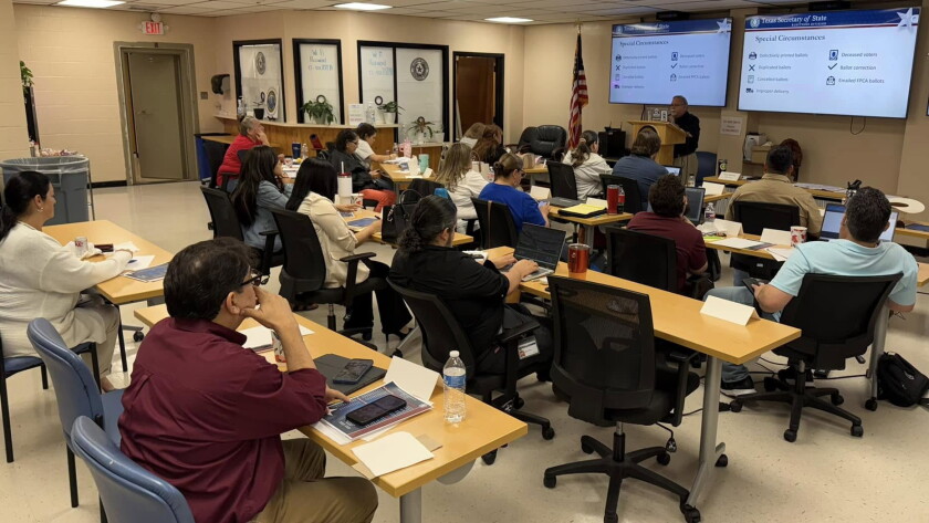 People seated at rows of tables facing a screen and an instructor as they participate in a regional training in the Cameron County elections office.