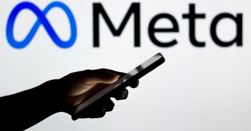 A person holding up a smartphone in the foreground. The background is white with the Meta logo in blue and black on it.
