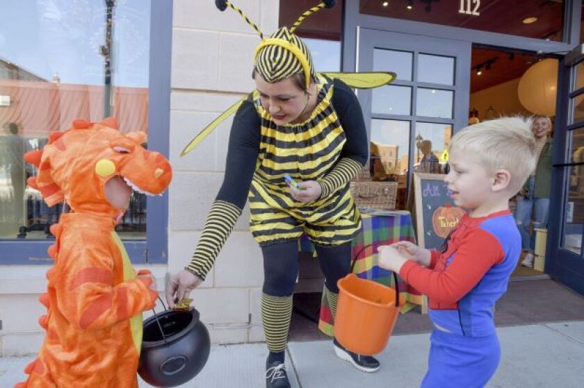 A person dressed in a bee costume gives out candy to children