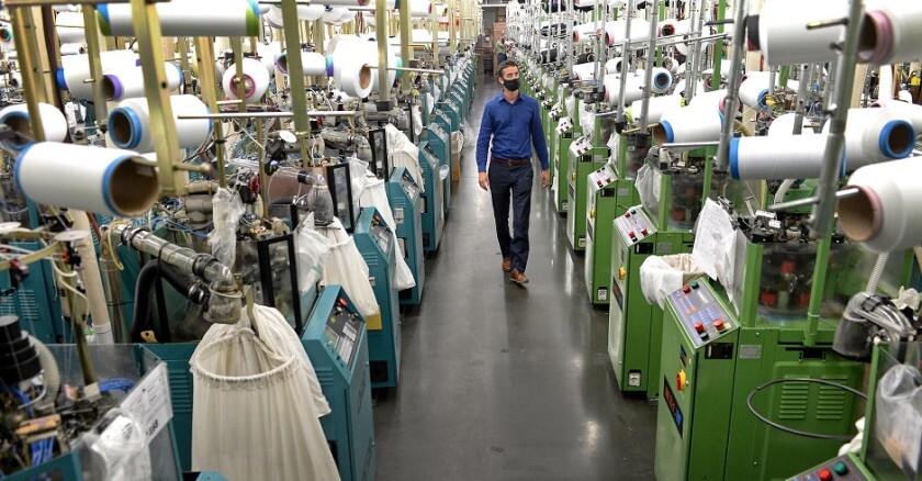 A man wearing a face mask walks through a factory.