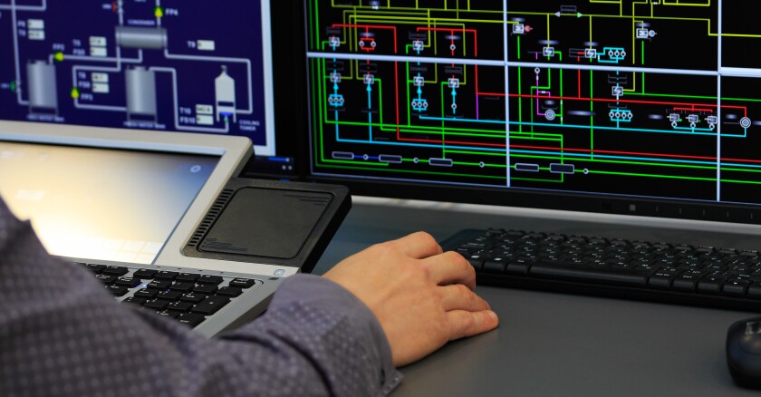Closeup of a person working on a computer in a control room.