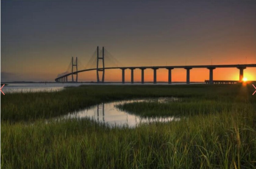 The Sidney Lanier Bridge with the sun very low behind it.
