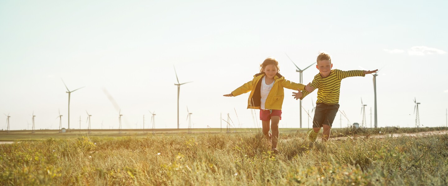 Little,Girl,And,Boy,Are,Running,In,Front,Of,Windmills.
