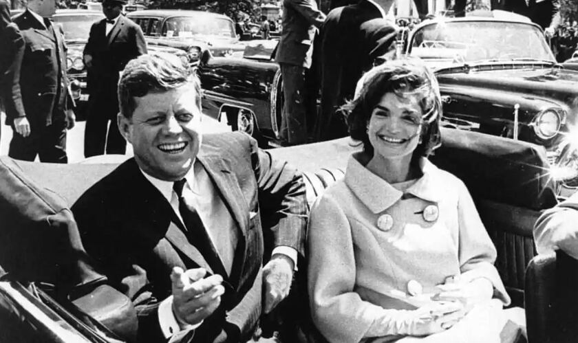 Black-and-white photo of U.S. president John F. Kennedy and first lady Jacqueline Kennedy sitting in a car.
