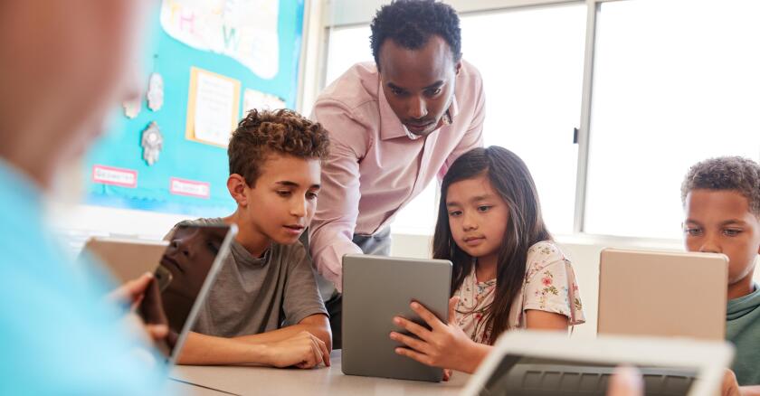 Teacher among school kids using computers in class