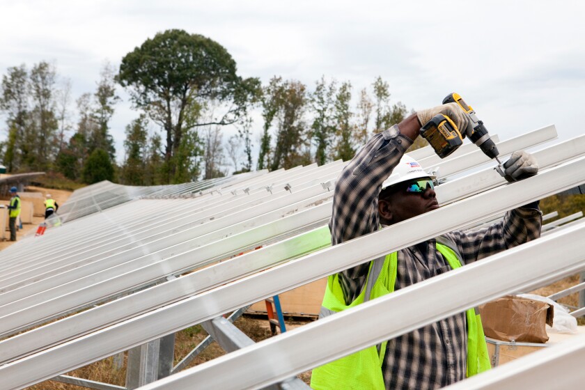 A man works to install solar panels.