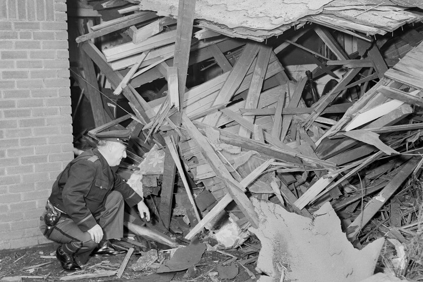 A police officer inspecting damage done to the home of civil rights leader Fred Shuttlesworth in 1950s Birmingham.