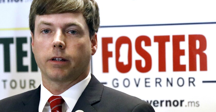 Mississippi's Robert Foster in front of a microphone and campaign sign.