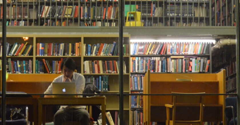A person working on a laptop in a library.