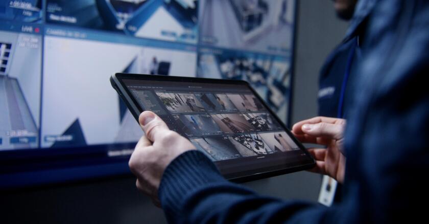 A person holding a tablet showing the feeds from multiple security cameras.