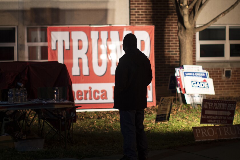 A+silhouette+of+a+person+standing+in+front+of+a+Trump+campaign+sign.