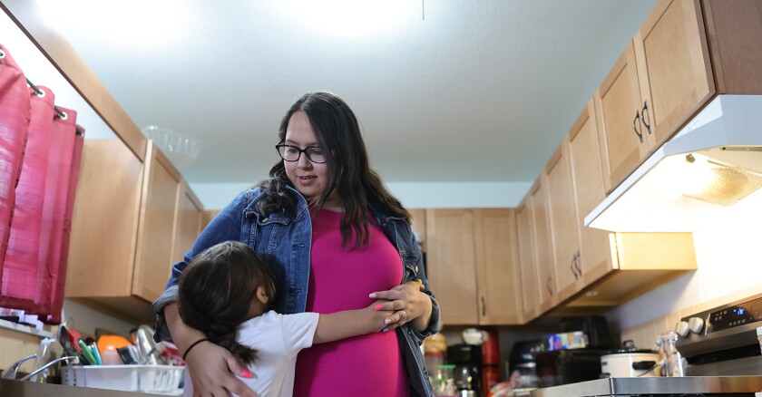 a woman hugs her child in a kitchen