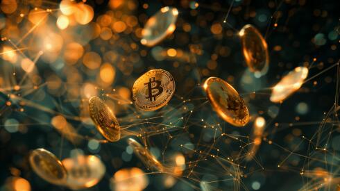 Multiple golden coins with the bitcoin logo on them falling across the image. Dark background.