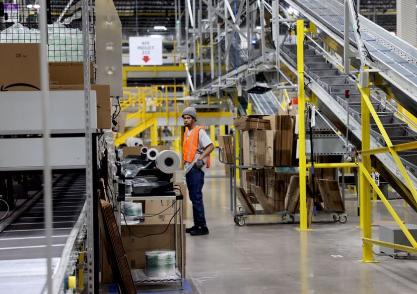 an Amazon worker stands in an aisle in the warehouse in Clay, N.Y.