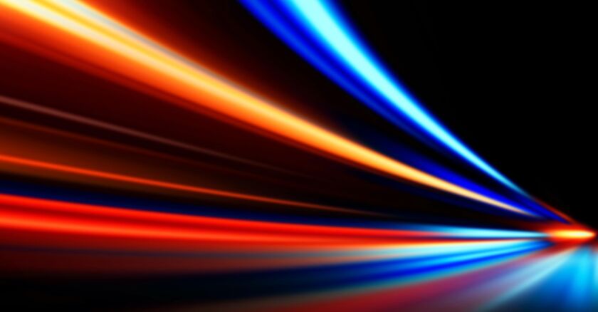 Blurred orange and blue lines against a dark background to indicate something moving very fast.