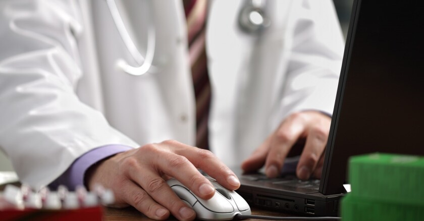 A person in a lab coat working on a computer.
