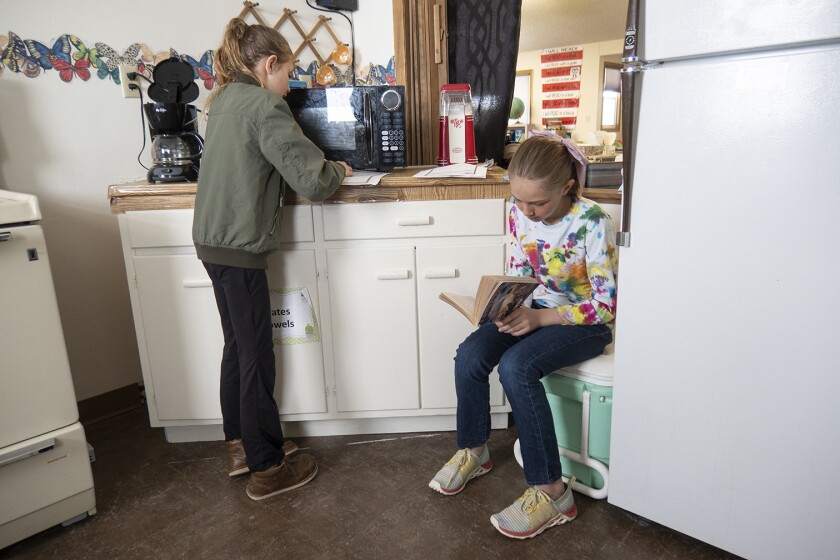 Two students doing schoolwork in a small kitchen.