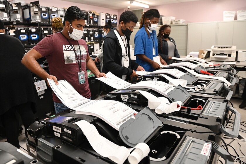 Workers in the Detroit Department of Elections inserting test ballots into machines during a public accuracy test.