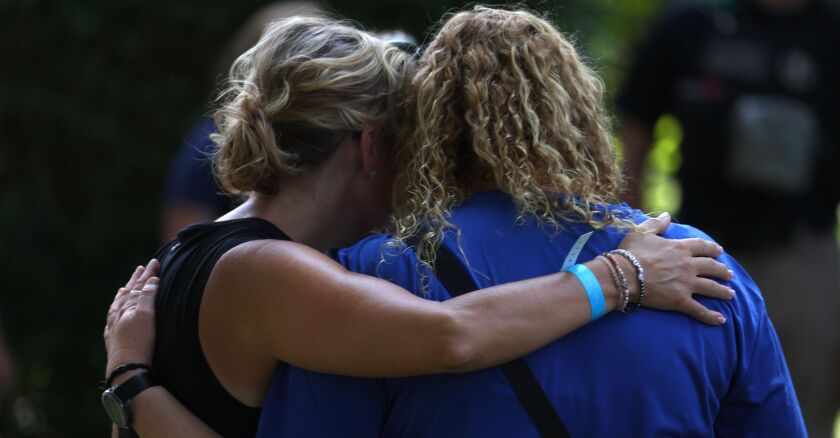 Two women hug during a remembrance ceremony