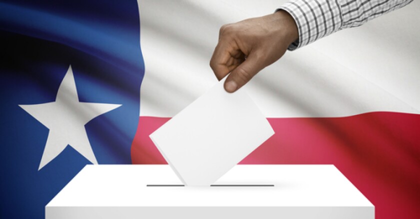 Closeup of a hand putting a ballot in a box with the Texas flag in the background.