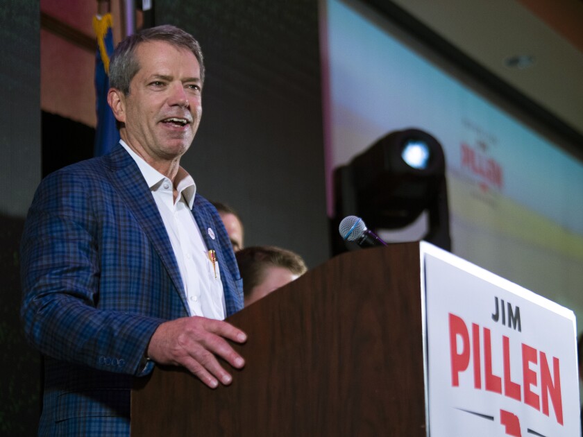 Jim Pillen standing at a podium smiling.