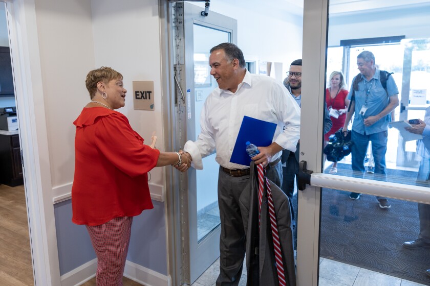 Andrew Ginther shaking hands with a woman greeting him at the entrance to Poplar Fen Place.