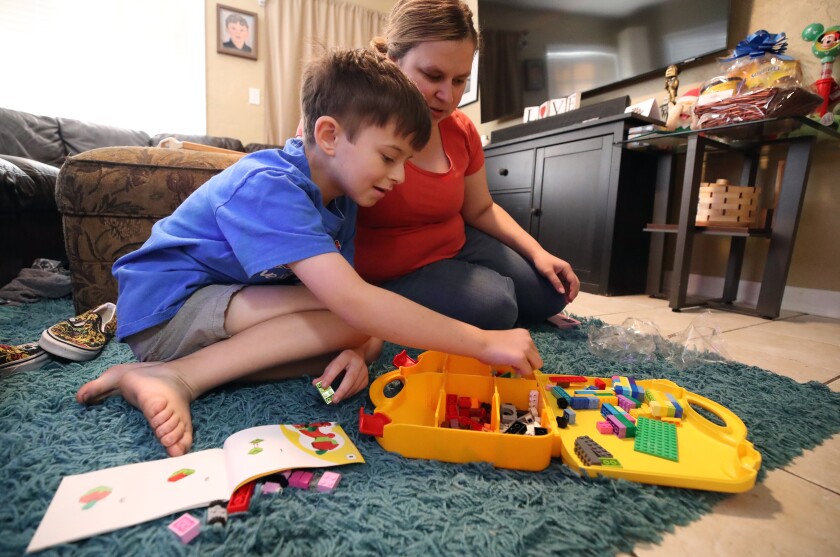 Erin Booth plays with Legos with her 9-year-old son, Landon, at their home in Orlando on Thursday, Dec. 26, 2024. Landon contracted leukemia during the COVID-19 pandemic and was able to get Medicaid for his treatment. He was one of 500,000 kicked off it because of unwinding and placed on KidCare, which covers medical expenses but not other things he needs such as occupational therapy, physical therapy and speech therapy. She was waiting for expansion of KidCare, hoping those services would become available. (Ricardo Ramirez Buxeda/Orlando Sentinel/TNS)