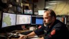 A person sitting in front of several computer monitors in an emergency communications center.
