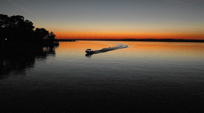 a boat on a river silhouetted by sunset